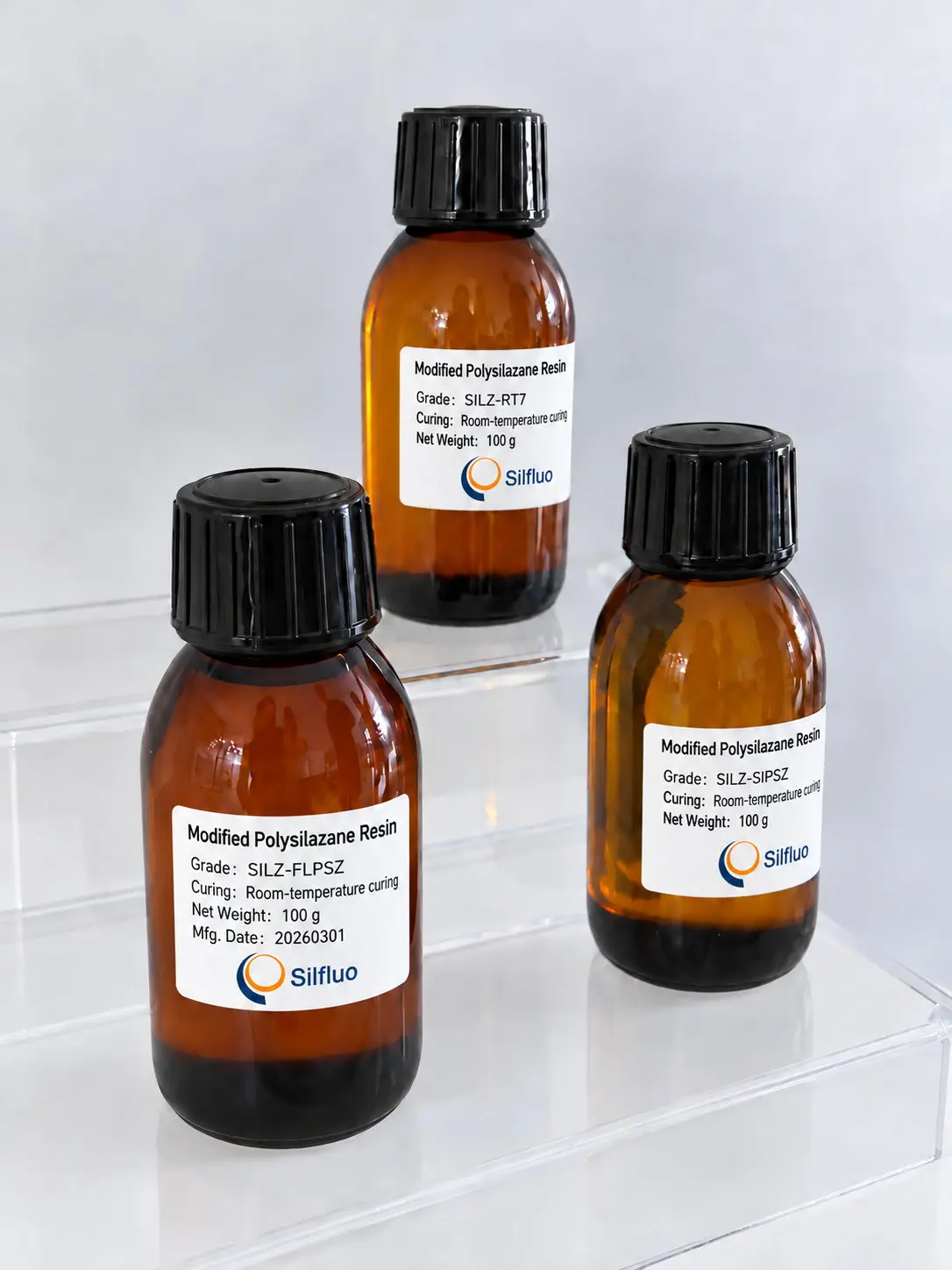 Three labelled 100 g amber glass sample bottles of modified polysilazane resin, grades SILZ-RT7, SILZ-FLPSZ and SILZ-SIPSZ, on acrylic risers